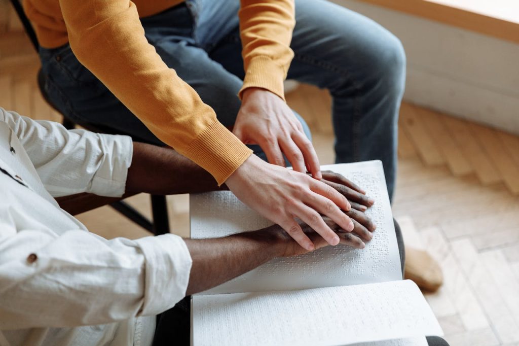 A Person Helping a Blind Person while using Braille